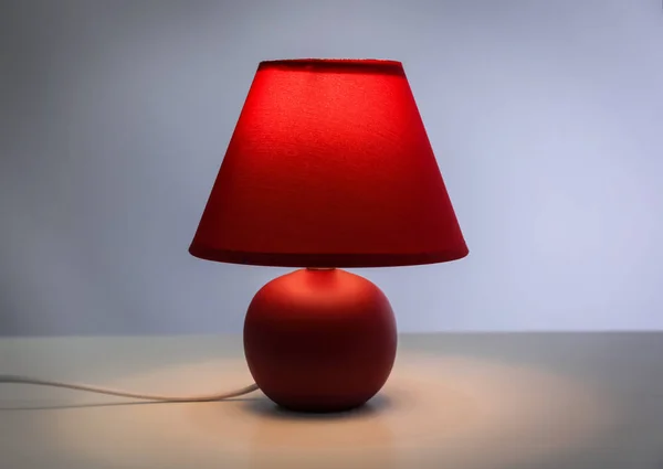 Stilvolle Lampe auf dem Tisch vor farbigem Hintergrund — Stockfoto