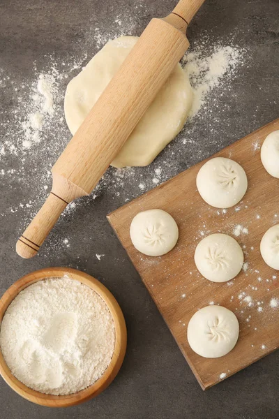 Placa de madeira com bolinhos de baozi crus na mesa — Fotografia de Stock