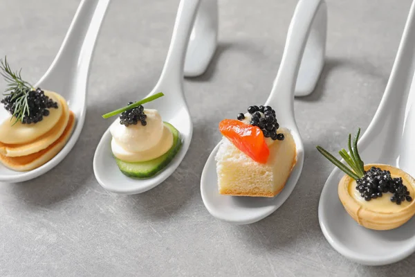 Lepels van canapeetjes met zwarte kaviaar op tafel — Stockfoto