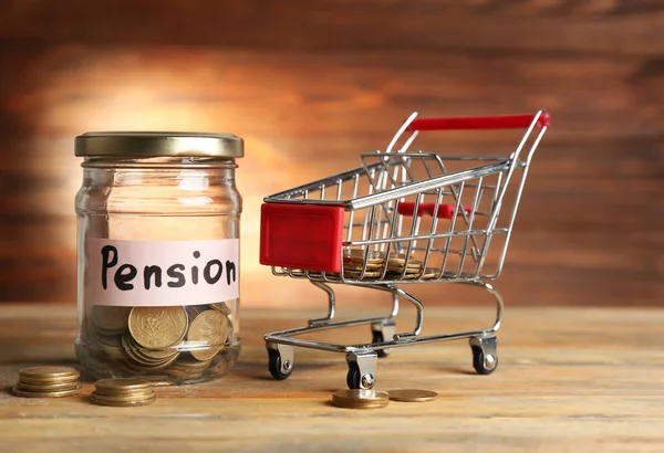 Monete in vaso di vetro con etichetta "PENSION" e mini carrello sulla tavola — Foto Stock