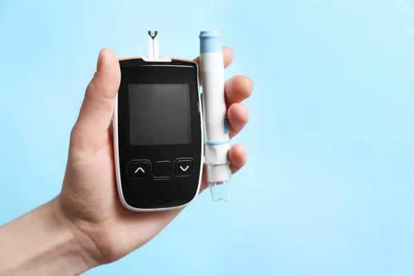 Frau mit digitalem Glukometer und Lanzettstift auf farbigem Hintergrund. Diabetes-Konzept — Stockfoto