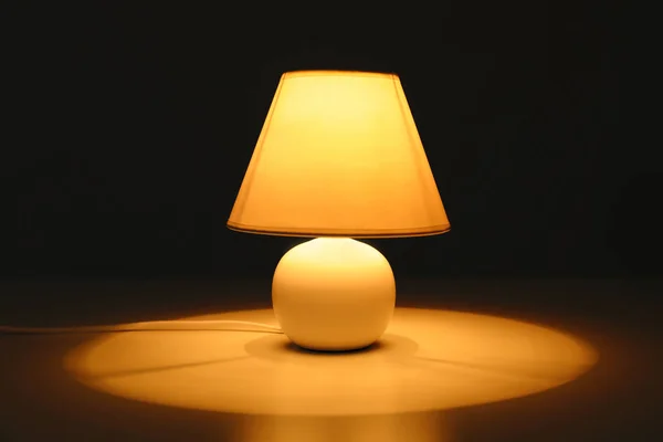 Stylish lamp on table in darkness