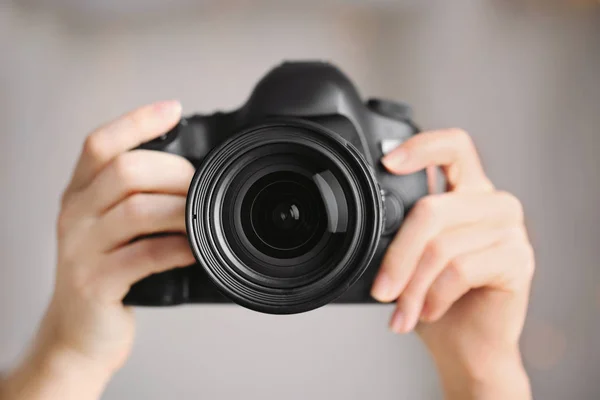 Fotografo femminile che tiene la fotocamera su sfondo sfocato — Foto Stock