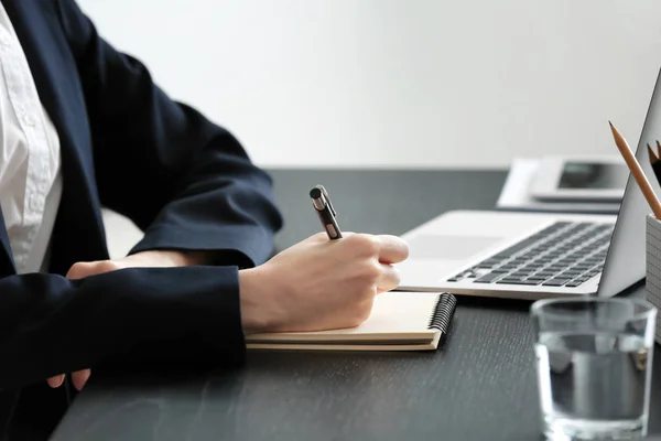 Kvinnlig student skriver i anteckningsboken vid bordet, närbild. Studera processen — Stockfoto