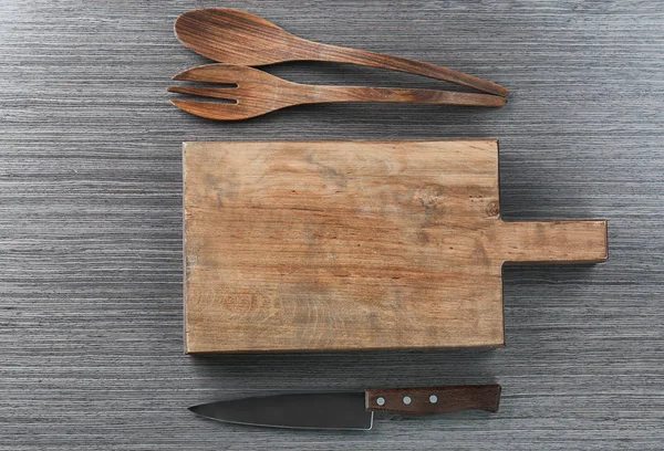 Placa de corte e utensílios de cozinha sobre fundo de madeira. Culinária master classes — Fotografia de Stock