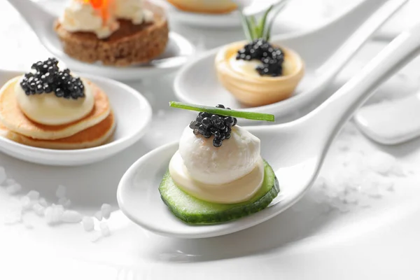 Skedar av kanapéer med svart kaviar på tallrik — Stockfoto