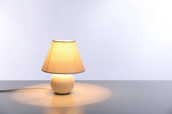 Stijlvolle lamp op tafel tegen de lichte achtergrond — Stockfoto