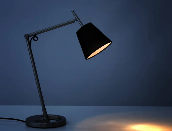 Stijlvolle bureaulamp op tafel in duisternis — Stockfoto