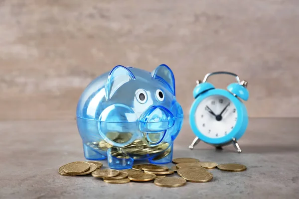 Piggy bank with coins and alarm clock on table. Pension planning