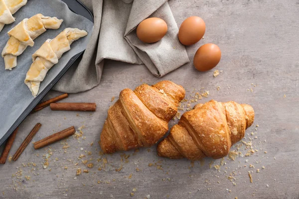 Composição com croissants crus e cozidos na mesa — Fotografia de Stock