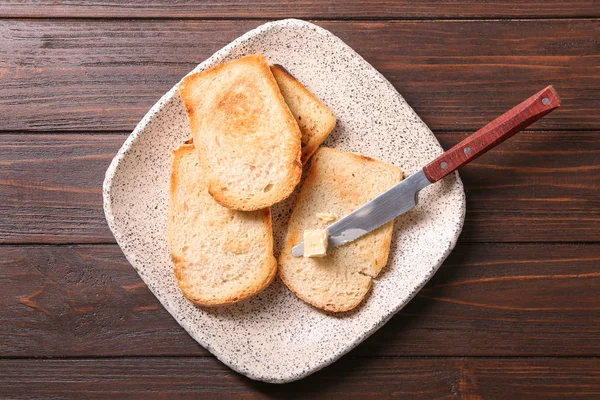 Plate with tasty toasted bread and butter on table — Stock Photo, Image