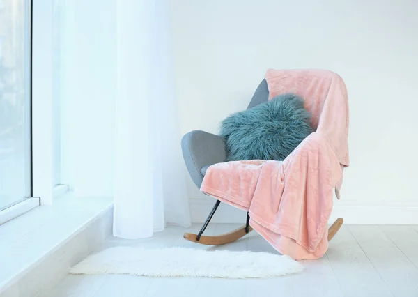 Soft pillow and plaid on armchair in room — Stock Photo, Image