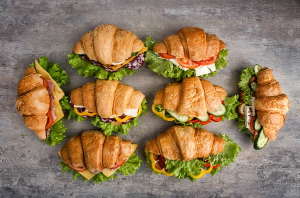 Deliciosos sanduíches de croissant no fundo cinza — Fotografia de Stock
