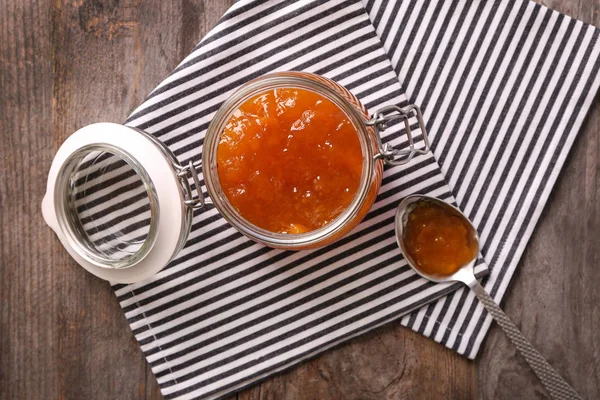 Jar and spoon with sweet jam on table Royalty Free Stock Images