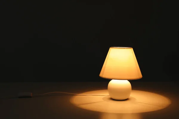Elegante lampada sul tavolo nel buio — Foto Stock