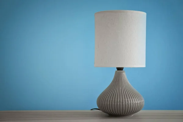 Stylish lamp on table against color wall