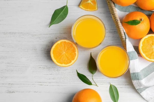 Vasos con zumo de naranja fresco y fruta sobre mesa de madera —  Fotos de Stock
