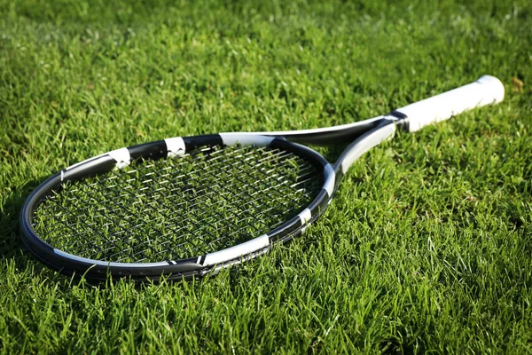 Modern tennis racket on green grass — Stock Photo, Image