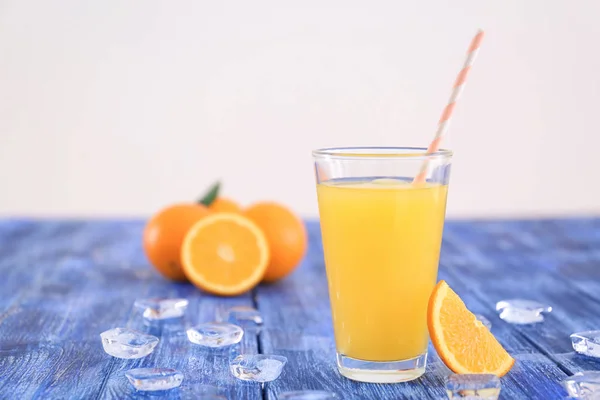 Glas met ijsblokjes, verse jus d'orange en fruit op de houten tafel — Stockfoto