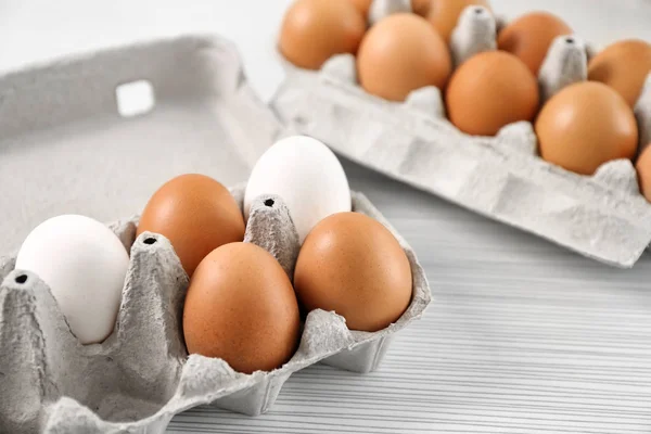 Envases con huevos de pollo en la mesa — Foto de Stock