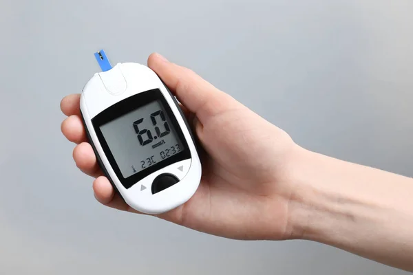 Frau mit digitalem Glukometer auf hellem Hintergrund. Diabetes-Konzept — Stockfoto