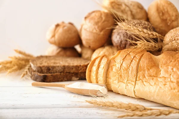 Freshly baked bread, flour and spikes on table — Stock Photo, Image