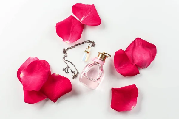 Butelkę perfum, naszyjnik i płatki róż na białym tle — Zdjęcie stockowe