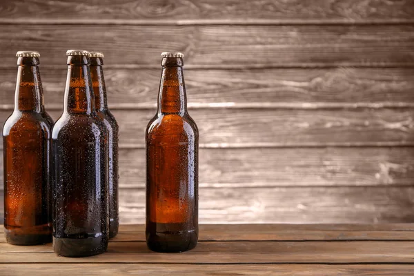 Birra fresca in bottiglie di vetro su sfondo di legno — Foto Stock