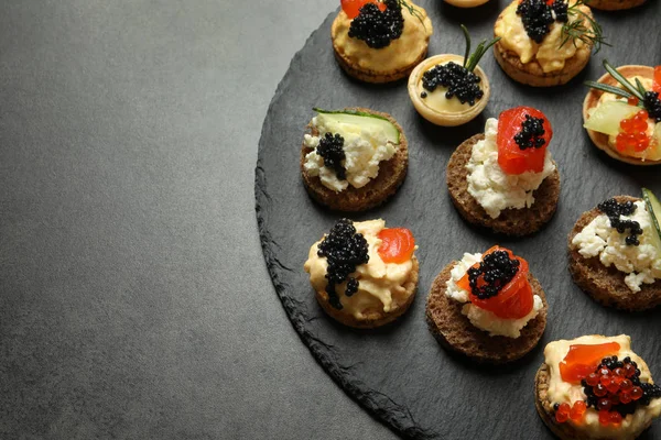 Delicious canapes with black caviar on slate plate — Stock Photo, Image