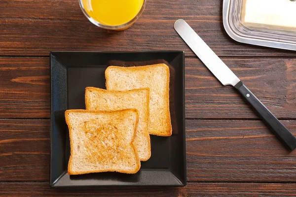 Plate with tasty toasted bread on wooden table — Stock Photo, Image