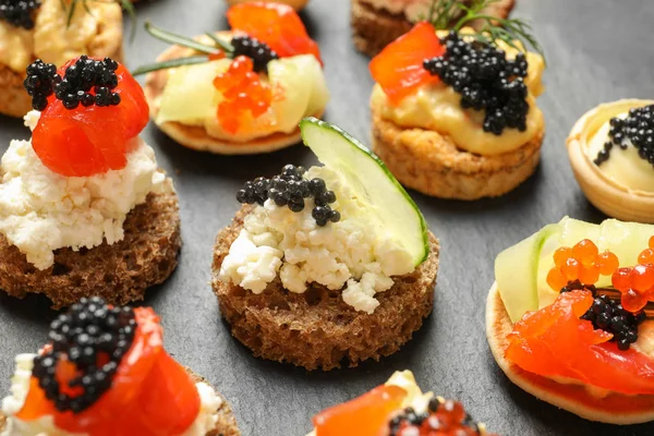 Delicious canapes with black caviar on dark background, closeup — Stock Photo, Image