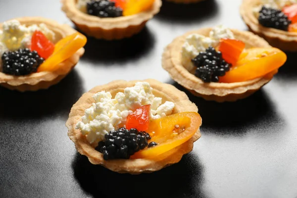 Deliciosos canapés com caviar preto no fundo escuro, close-up — Fotografia de Stock