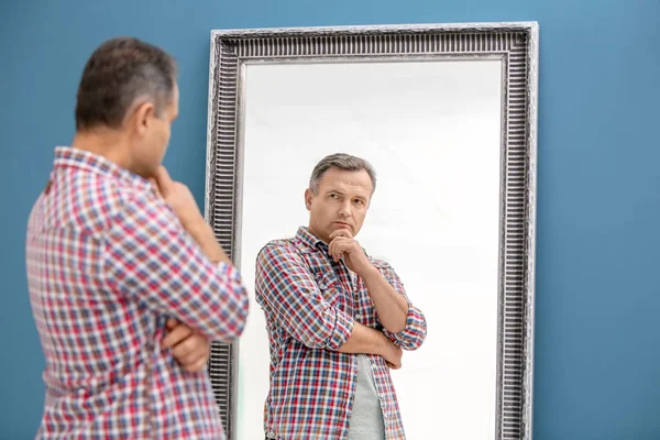 Homme mûr réfléchi debout près du miroir à la maison — Photo