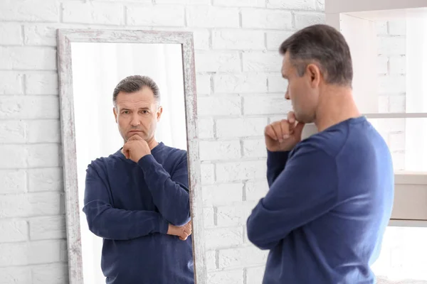 Homme mûr réfléchi debout près du miroir à la maison — Photo