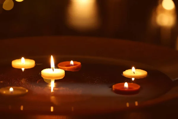 Velas ardientes flotando en el plato —  Fotos de Stock