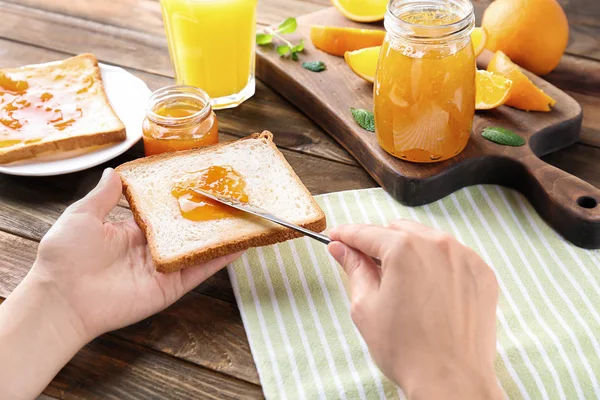 Mujer extendiendo dulce mermelada en tostadas sobre la mesa — Foto de Stock