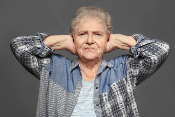 Ältere Frau, die ihre Ohren vor grauem Hintergrund verdeckt. Hörprobleme — Stockfoto