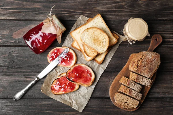 Delicious toasts with sweet jam on wooden table — Stock Photo, Image