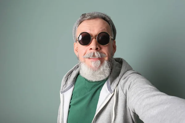Feliz hombre mayor en traje hipster tomando selfie sobre fondo gris —  Fotos de Stock