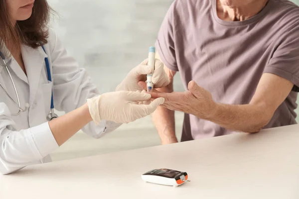 Doctor measuring blood sugar level of diabetic patient in clinic — Stock Photo, Image