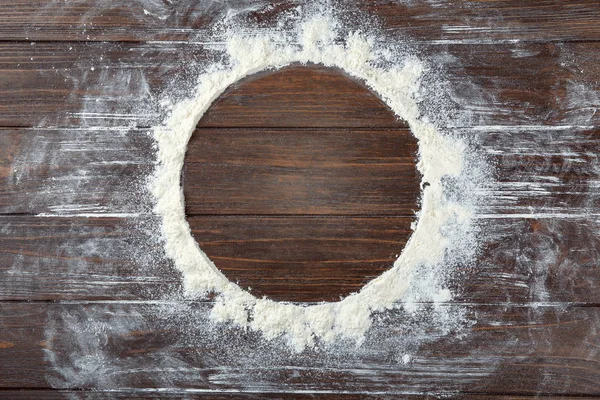 Rund ram gjord av mjöl på trä bakgrund, ovanifrån — Stockfoto