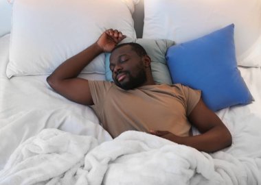 Adam yatakta uyuyor.