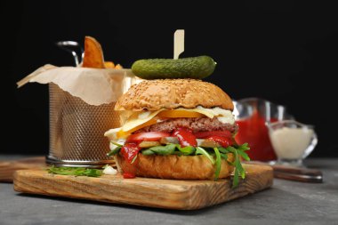 Lezzetli hamburger ve patates ahşap tahta karşı koyu arka plan üzerinde