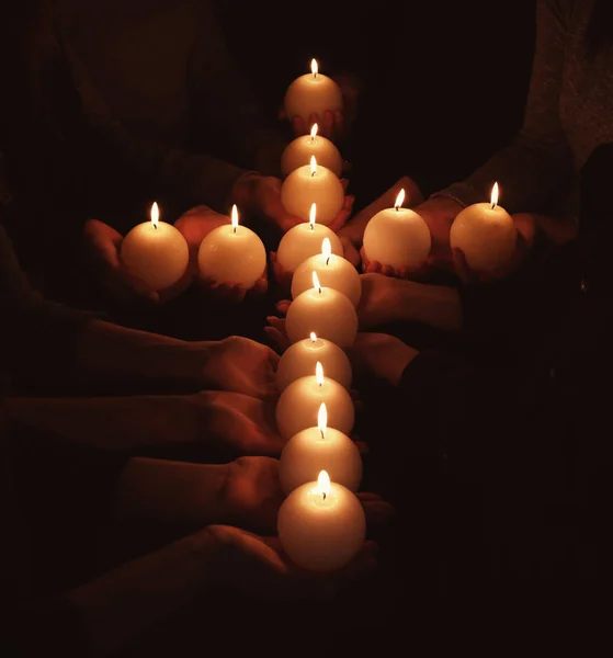 Gente con cruz hecha de velas encendidas en la oscuridad —  Fotos de Stock