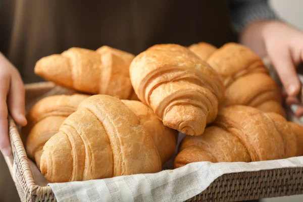 Woman holding wicker tray with delicious croissants, closeup — Stock Photo, Image