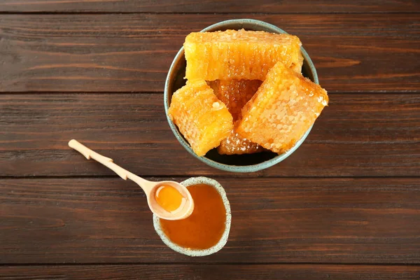 Miski z słodki miód i grzebienie na drewnianym stole — Zdjęcie stockowe