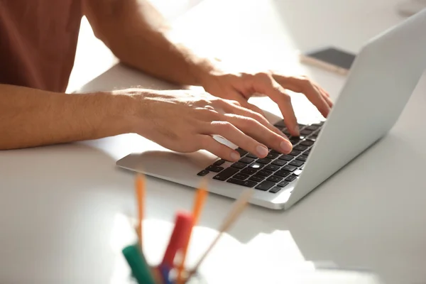 Молодой человек работает с ноутбуком в офисе, крупным планом — стоковое фото