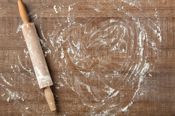 Farinha dispersa e rolo em mesa de madeira — Fotografia de Stock