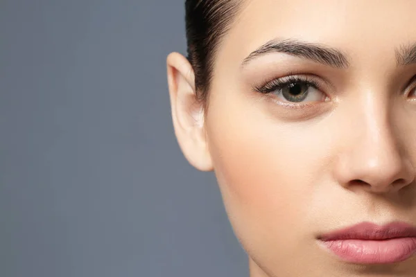 クローズ アップ、灰色の背景に自然な眉を持つ若い女性 — ストック写真