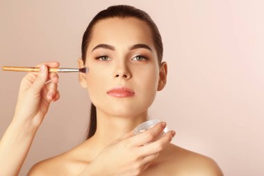 Kadının yüzüne karşı açık renkli makyaj uygulayarak profesyonel visage sanatçı